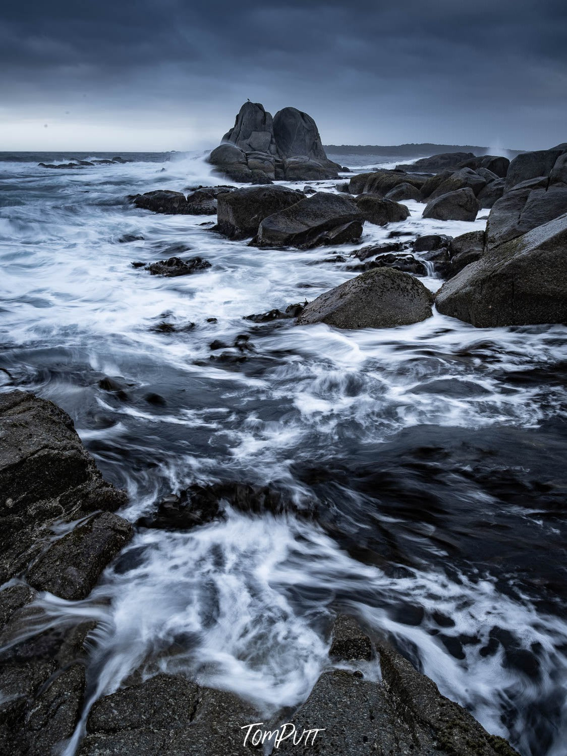 A stormy view of a sea with heavy greyish stones and flowing water with bubbles, Bay of Fires Seas, Tasmania