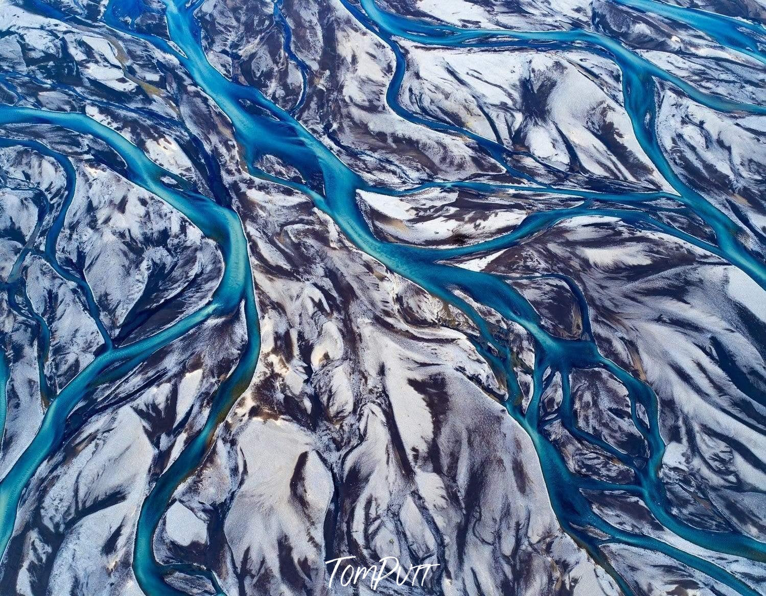 A breathtaking view of a large snow-covered area with thin lines of flow of clear blue water, Blue Ribbon Iceland
