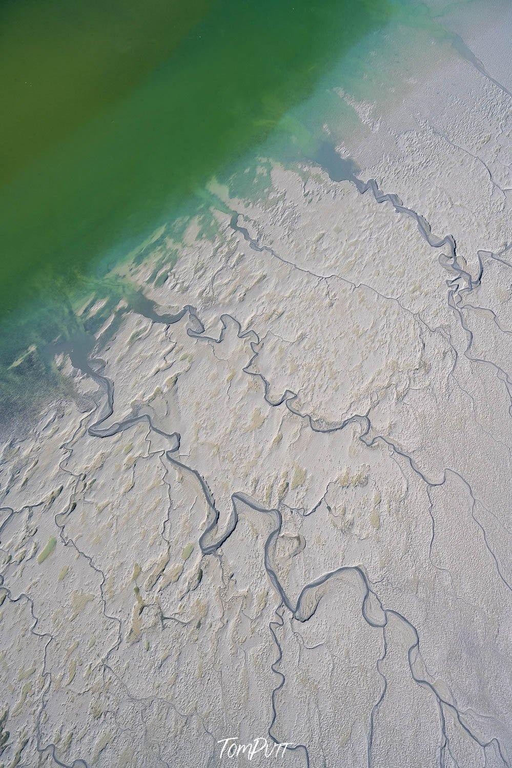 A deep sea-green oceanic surface is connecting with a white sand-like surface having long and clear cracks on it, Broome No.13