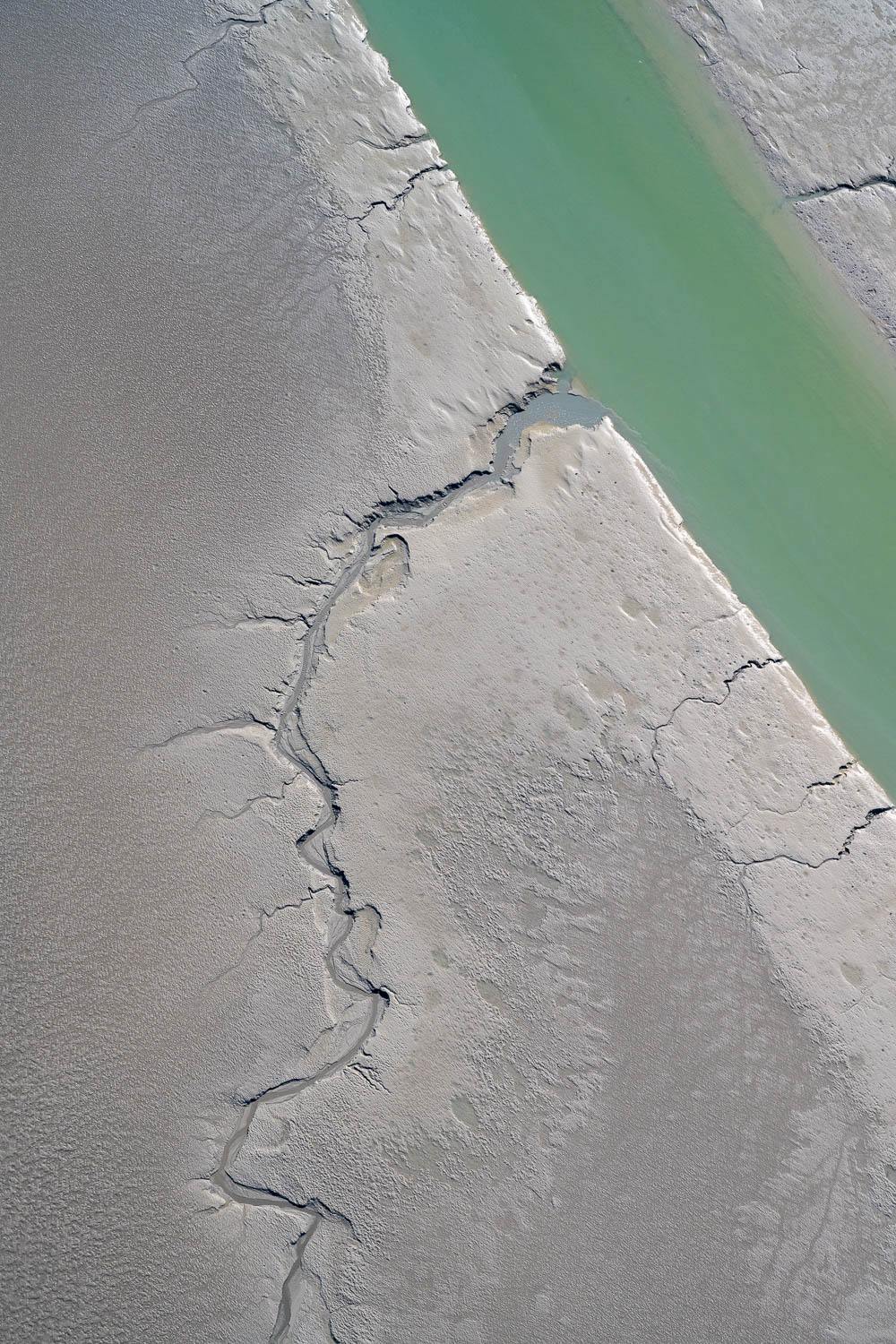 A field of sand with green thick line water flowing liquid with a long crack on the land, Broome #8