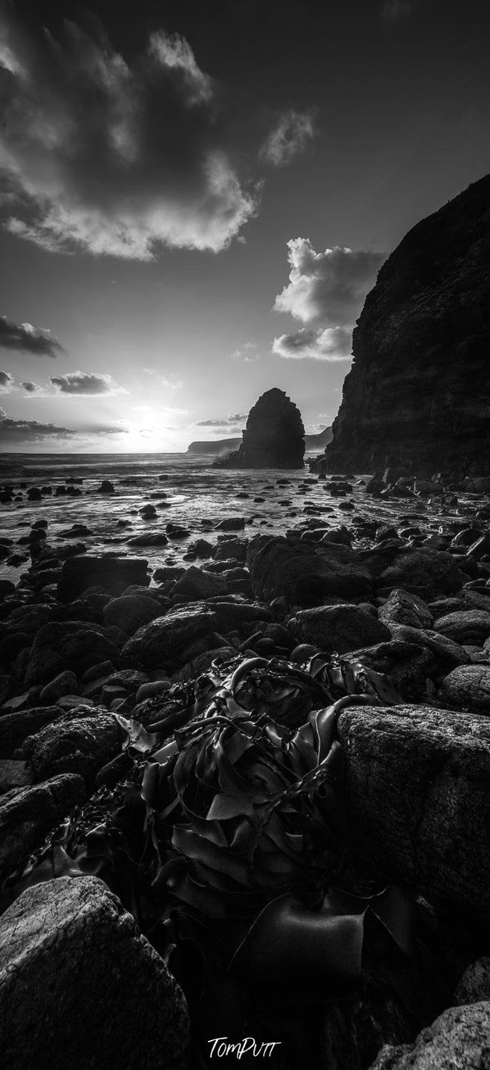 A night view of the seashore with a lot of small stones penetrating in the sand and a couple of giant stones standing tall in the feet water, Cairns Bay Pulpit - Mornington Peninsula