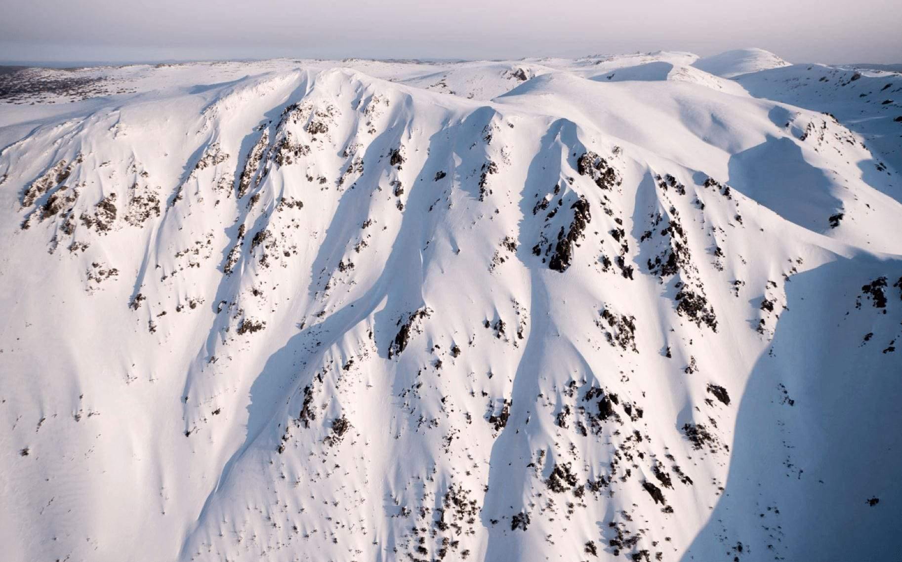 A giant mountain fully covered with fresh snow and some spots of wet sand on it, depicting a white ice-cream with chocolate chips on it, Carruthers - Snowy Mountains NSW
