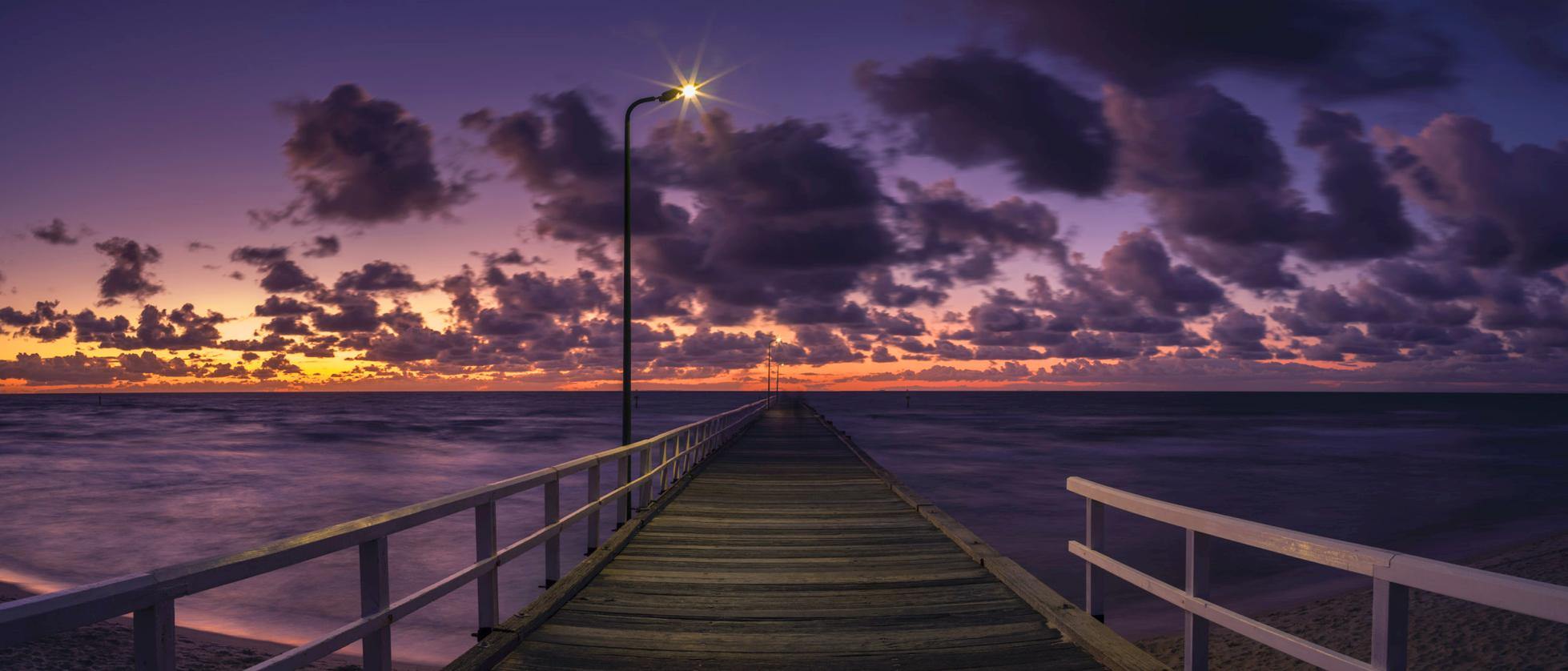 A beautiful wood bridge on the edge of the sea with silent surroundings and some dark thick clouds in the far background, Clouded Dusk, Seaford - Mornington Peninsula VIC