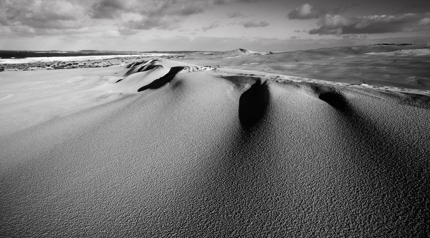 Naturally shaped sand with an upper corner and a static land behind it, a black and white-colored art, Coastal Sand Dune, Eyre Peninsula