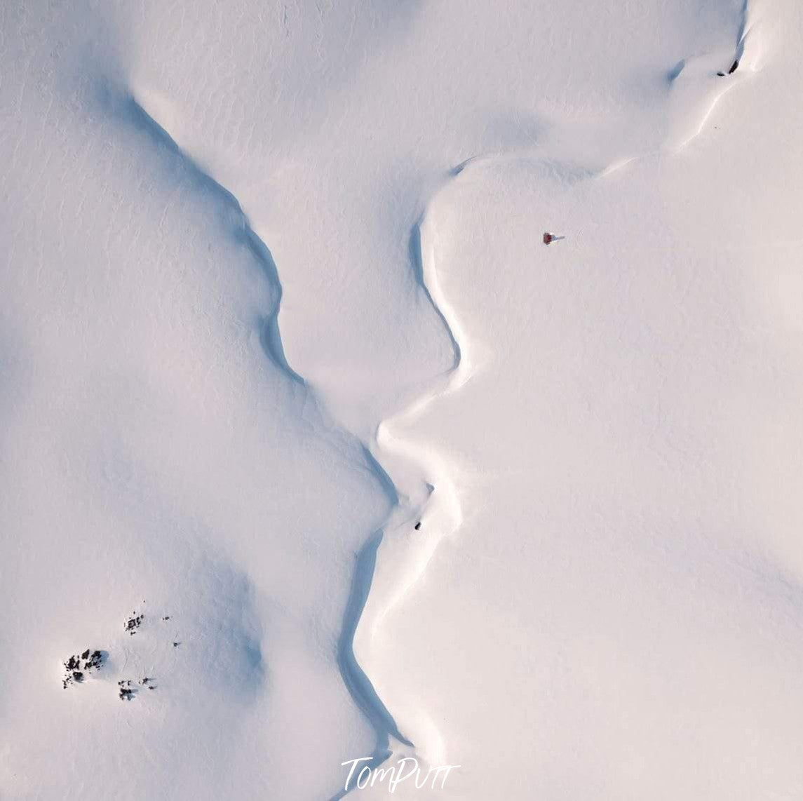 An aerial view of a snow-covered area forming a convergence in the middle, and some small black spots in the left bottom corner, Convergence - Snowy Mountains New South Wales