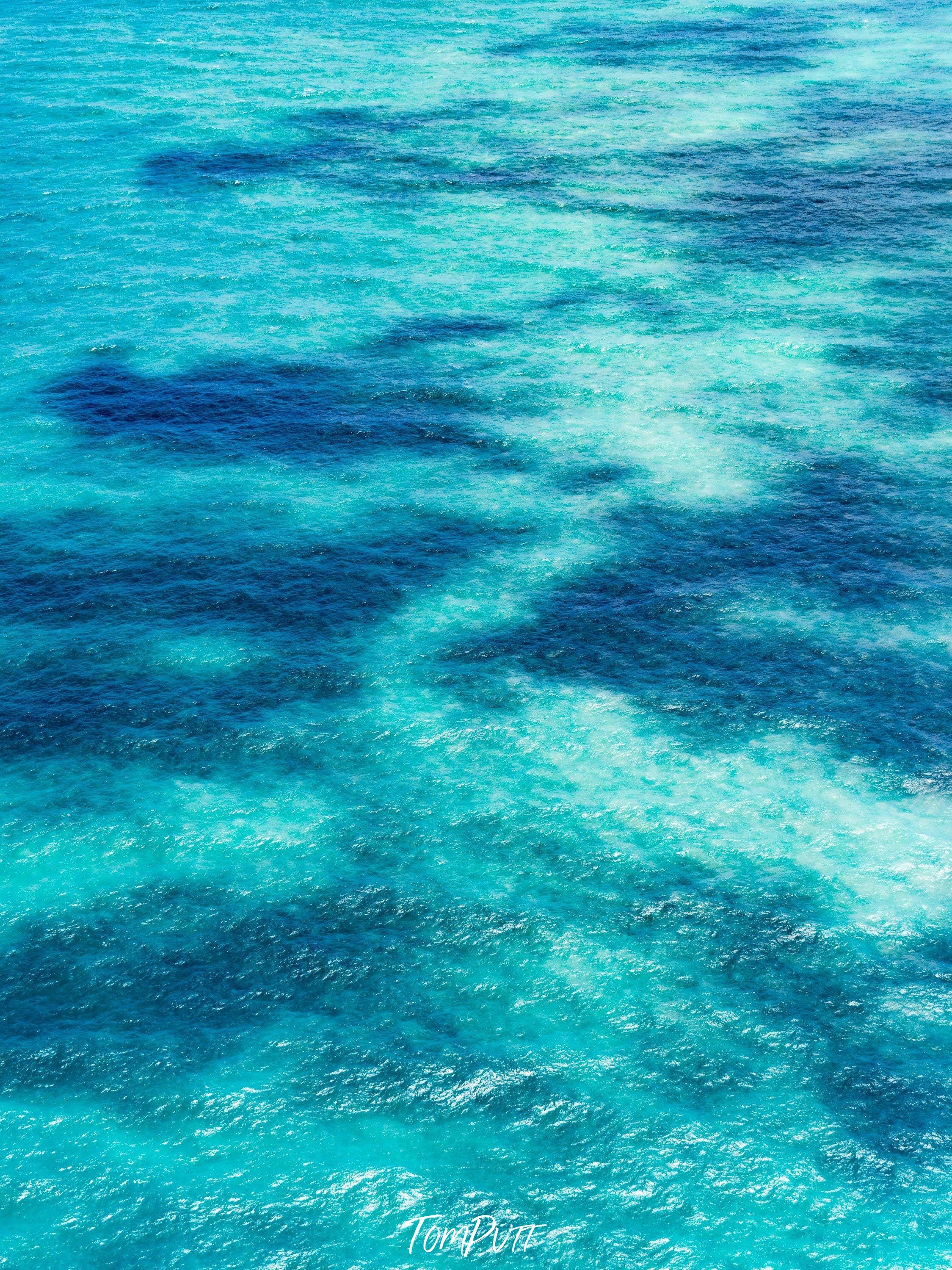 A shiny sky-blue ocean with the parallel shadow of some random shapes inside the water, Dancing Shadows