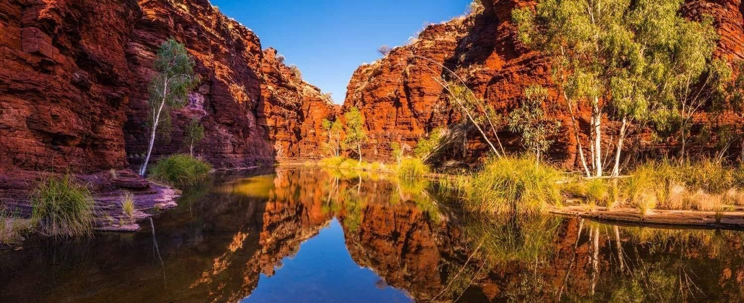 A small lake between two giant mountain walls, and a reflection of the scene in the water, Kalamina Gorge - Karijini, The Pilbara 