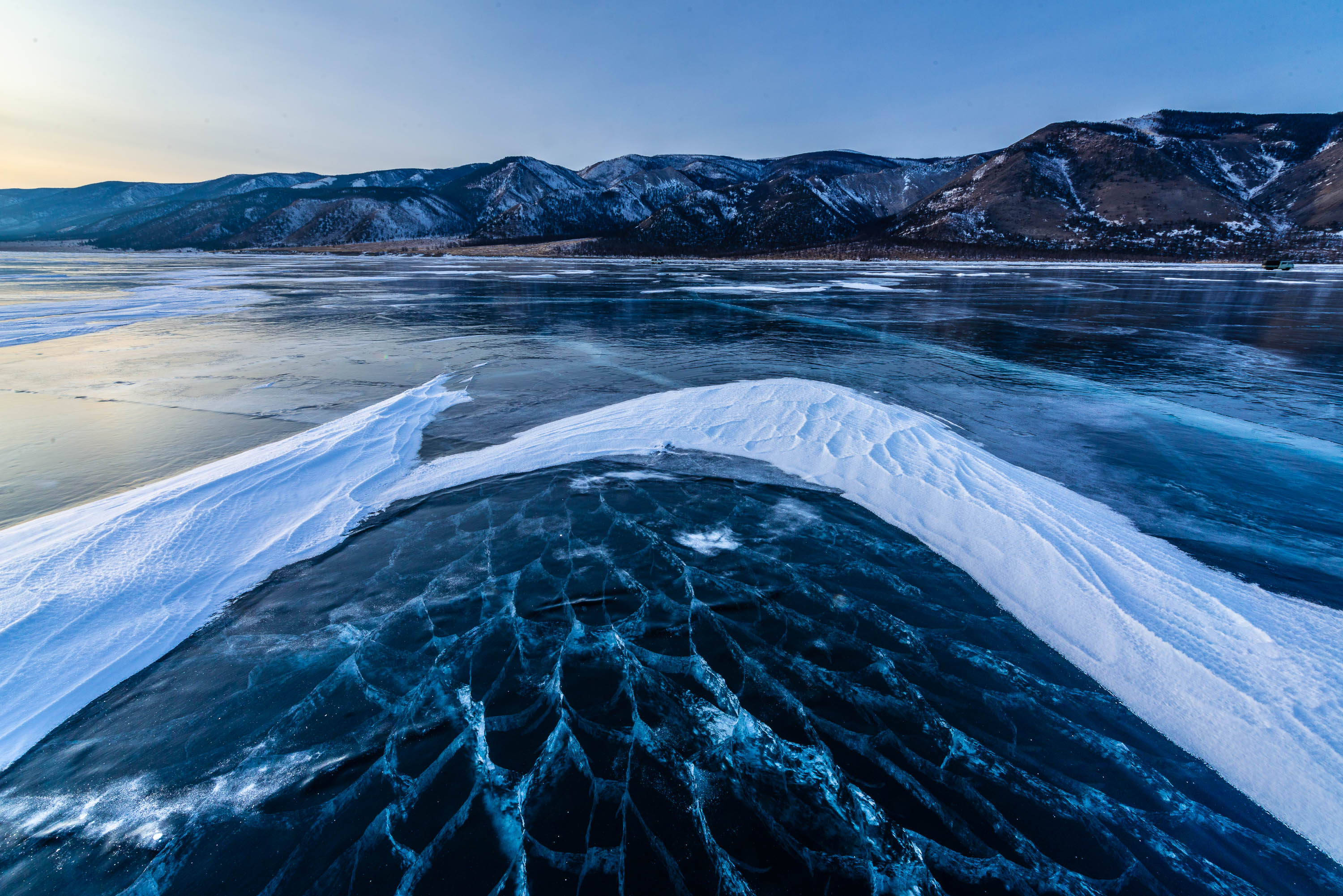 A frozen lake with some fresh snow, and a long mountain wall in the background, Lake Baikal #27, Siberia, Russia