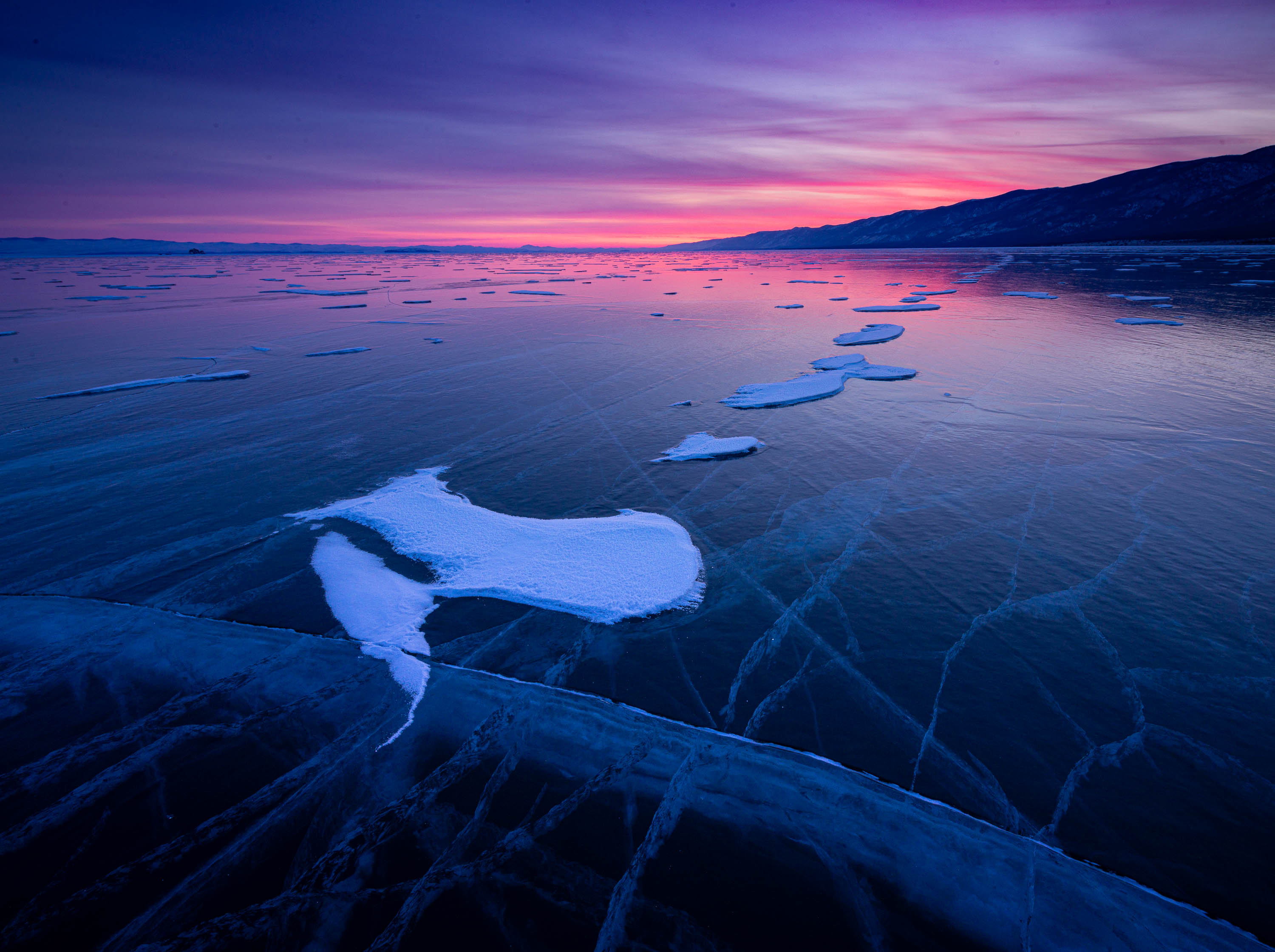 A frozen lake with some fresh snow, and a pinkish effect in the background, Lake Baikal #33, Siberia, Russia