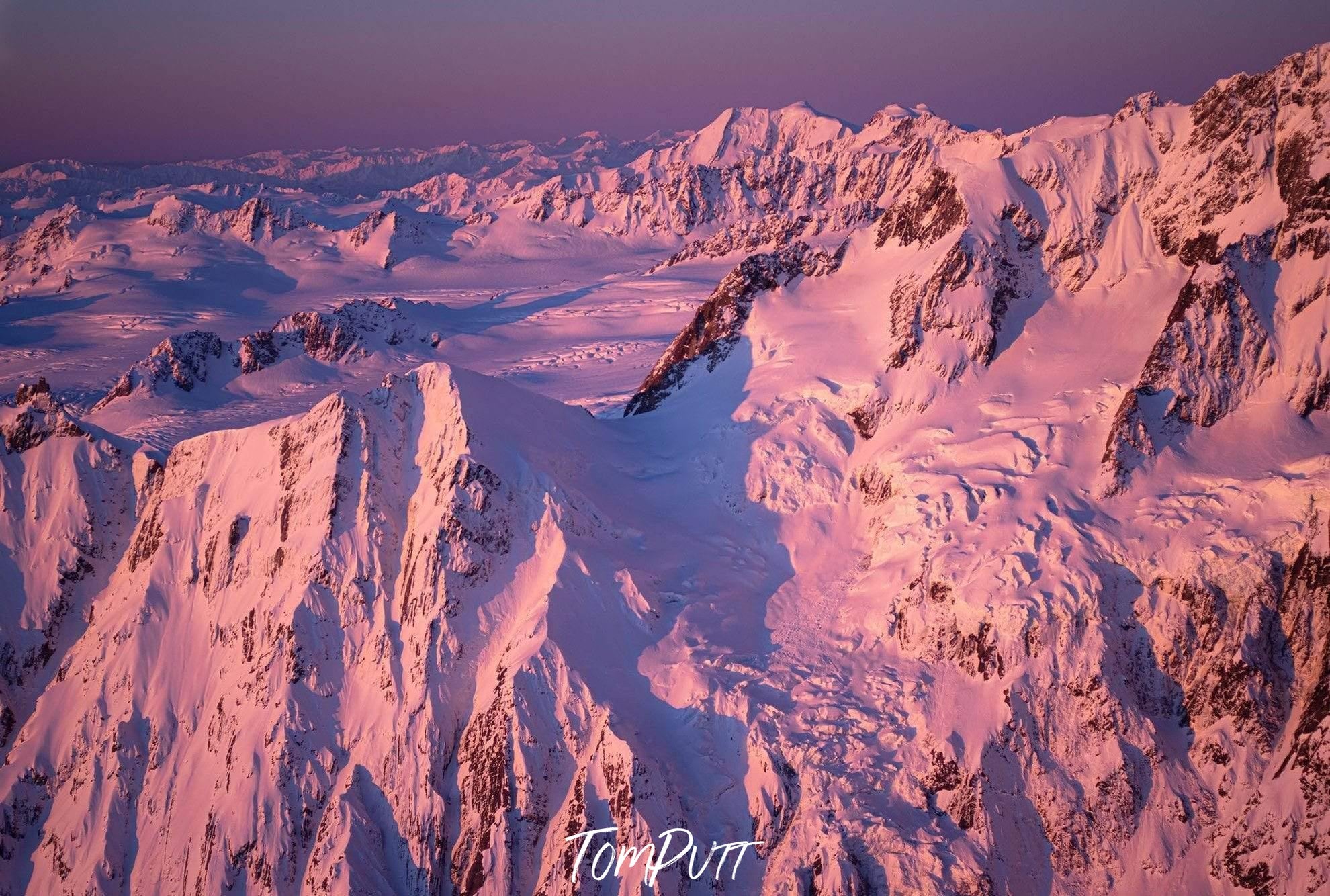 Aerial view of pinkish giant snow-covered mountain walls, Magenta Alps