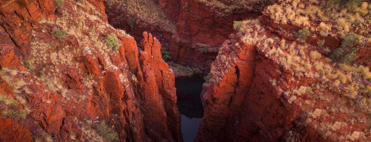 Aerial view of the peaks of giant mountain walls with a small water standing in a deep below, Oxer Lookout - Karijini, The Pilbara