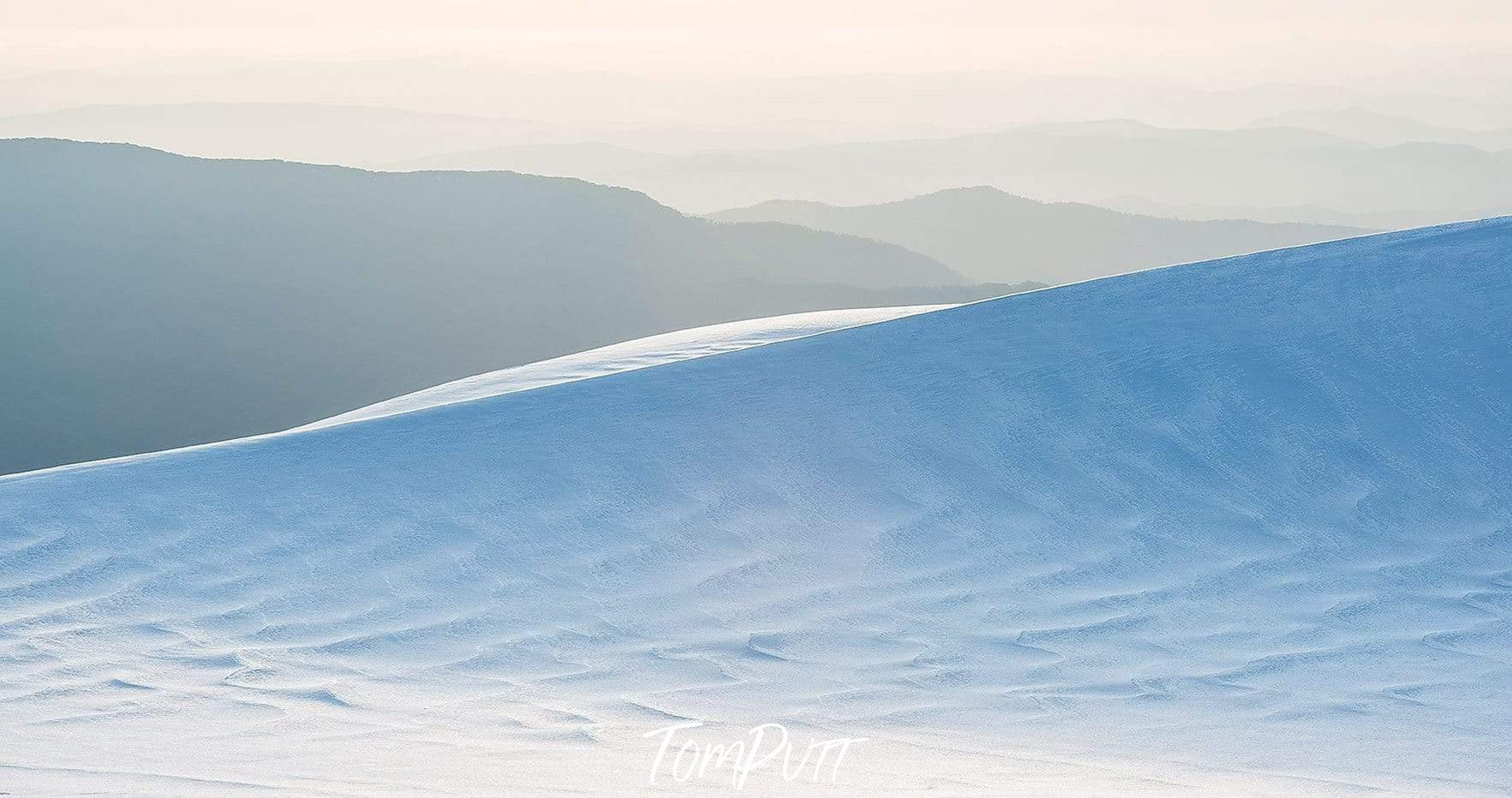 A beautiful afternoon view depicting a snowy smoke-colored mountain, and the dark dim mountains in the background, Snowy Mountains - New South Wales