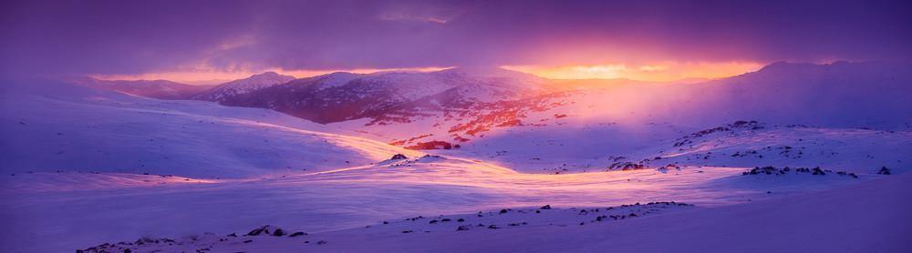 A snowy hill area fully covered under the snow with snow mounds with a beautiful scene of the rising sun spreading sunlight in the area, Charlotte Dawn New South Wales