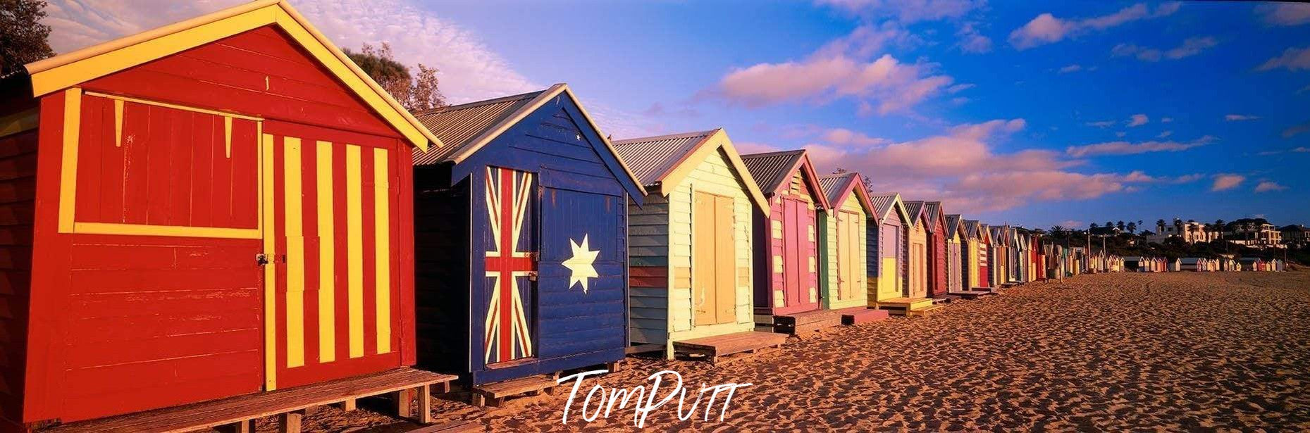 Similar shapes but different colors of huts with different flags painted on, True Blue - Brighton VIC