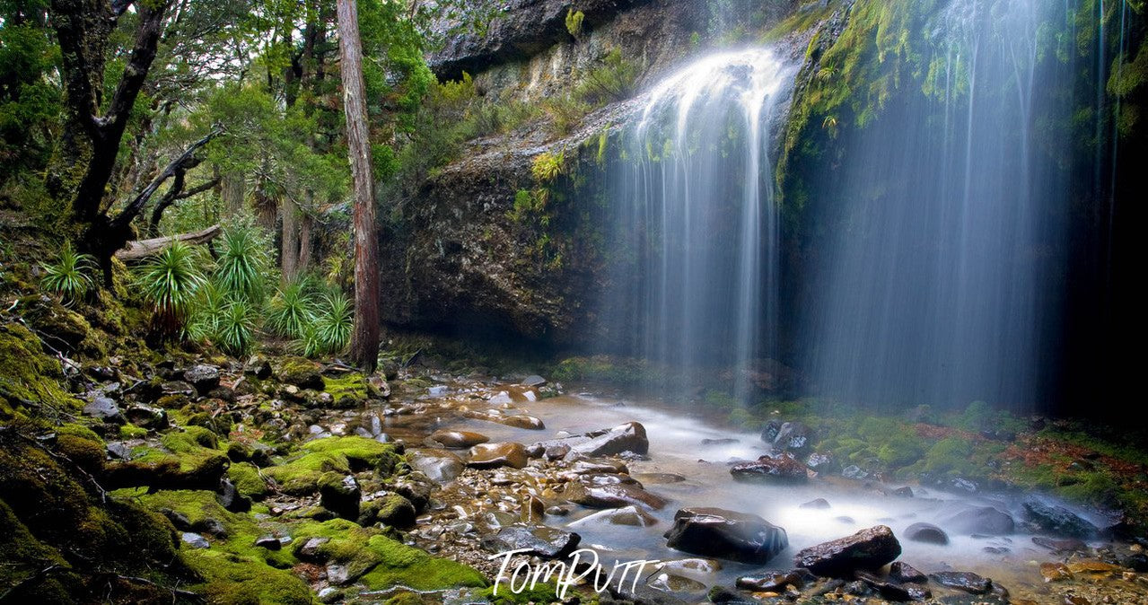 Waterfall from a green mountain wall, some bushes adjacent to the lake, Cradle Mountain #28, Tasmania