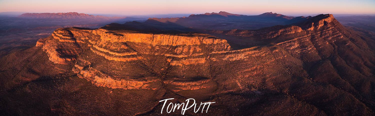 Long golden mountain wall with partially hitting sunlight, Wilpena Pound, Flinders Ranges from the air