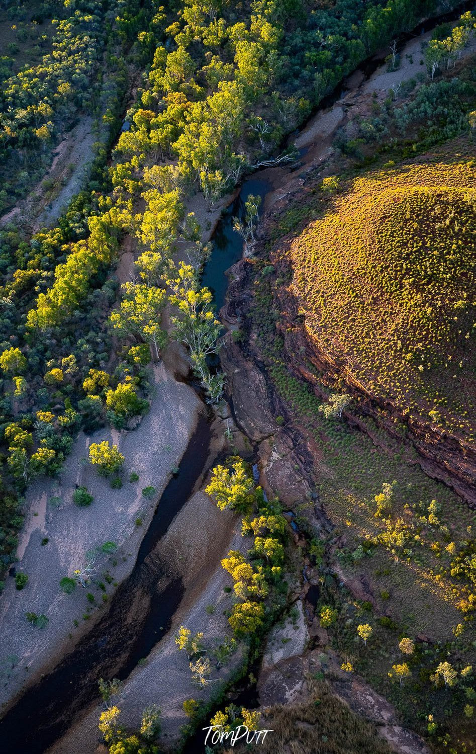 Aerial view of a sand mound with some greenery spreading in a curvy line