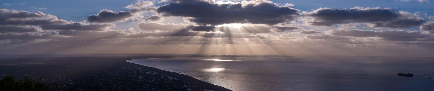 A landscape shot of the early morning, seashore with dense clouds over it and the Sun is rising, spreading the sunlight, Arthurs Seat Sunrays - Mornington Peninsula 