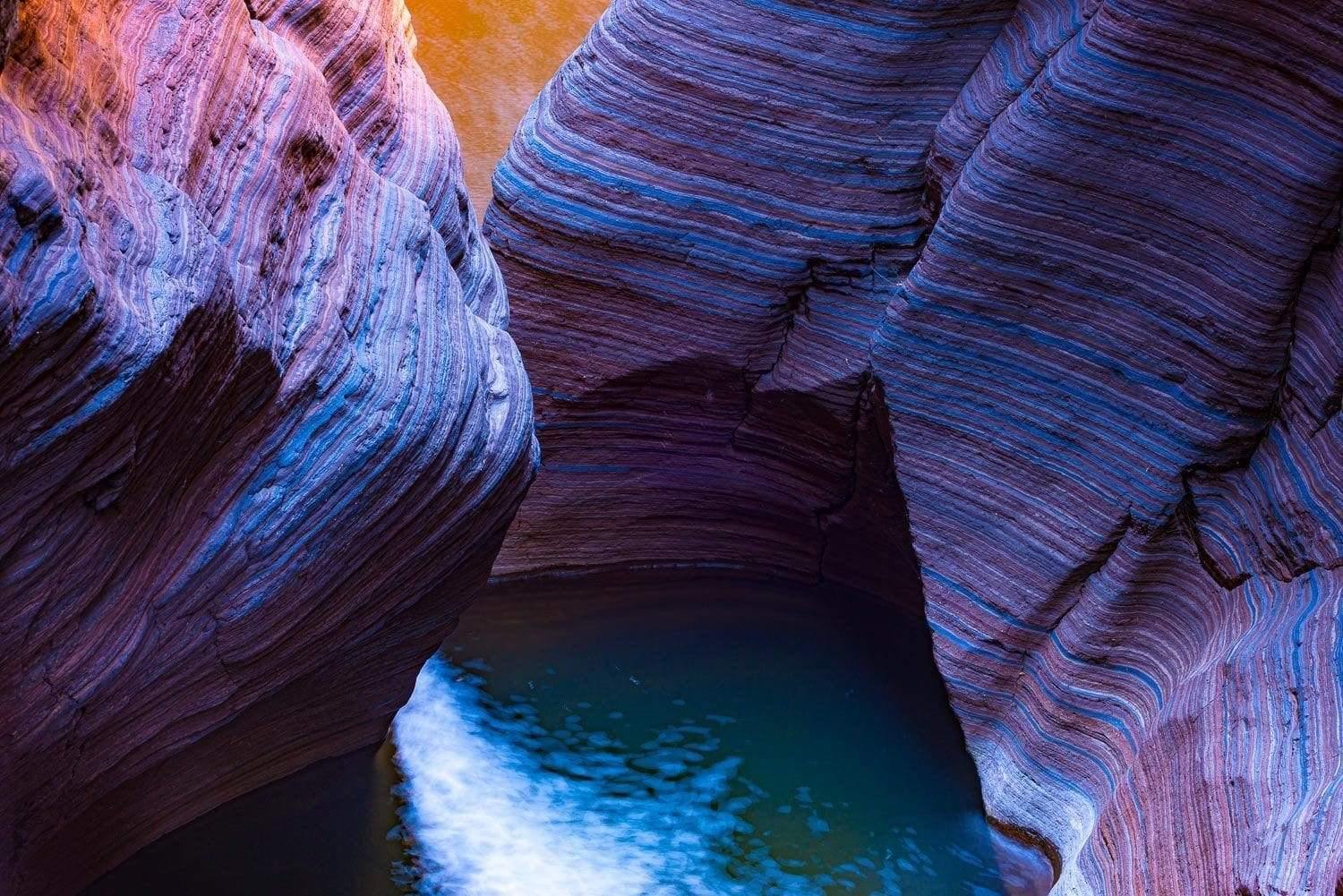 A colorful thin lining texture on the giant mountain stones standing tall with the flow of water below, Banded Gorge - Karijini, The Pilbara