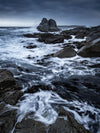 A stormy view of a sea with heavy greyish stones and flowing water with bubbles, Bay of Fires Seas, Tasmania