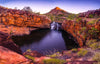 A small watercourse between a rocky wall of red bricks and a small waterfall on the front far corner, and a mound with little bushes and grass in the background, Bell Gorge - Gibb River Road, The Kimberley WA
