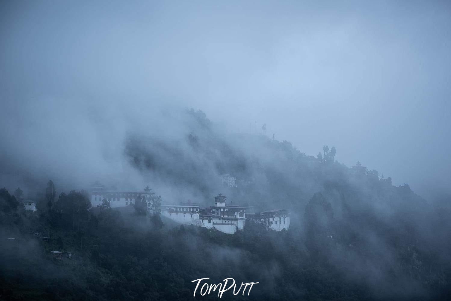 A fort on the edge of the hills with high mountains and greenery around it, and some great smoke effect on the entire picture, Bhutan Zhong