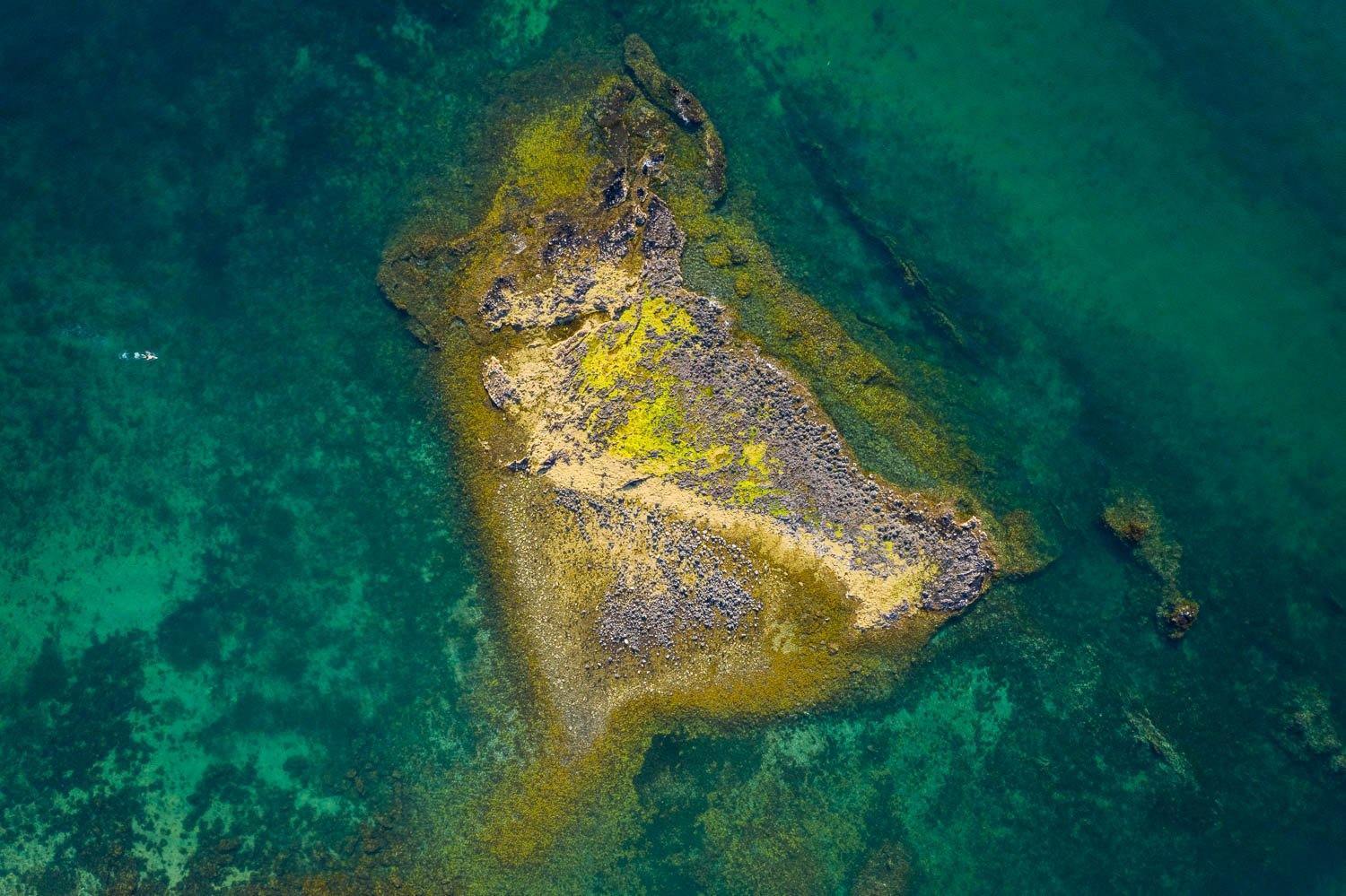 An aerial view of a beautiful parrot-colored green island with a lot of greenery and a cold deep sea-green sea around it, Bird Rock, Mt Martha - Mornington Peninsula VIC
