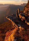 A close-up view of Giant Mountain stones on a high area with a huge grassy mound below them, and some other mountains and rocks in the background, Boroka Dawn - The Grampians, VIC 