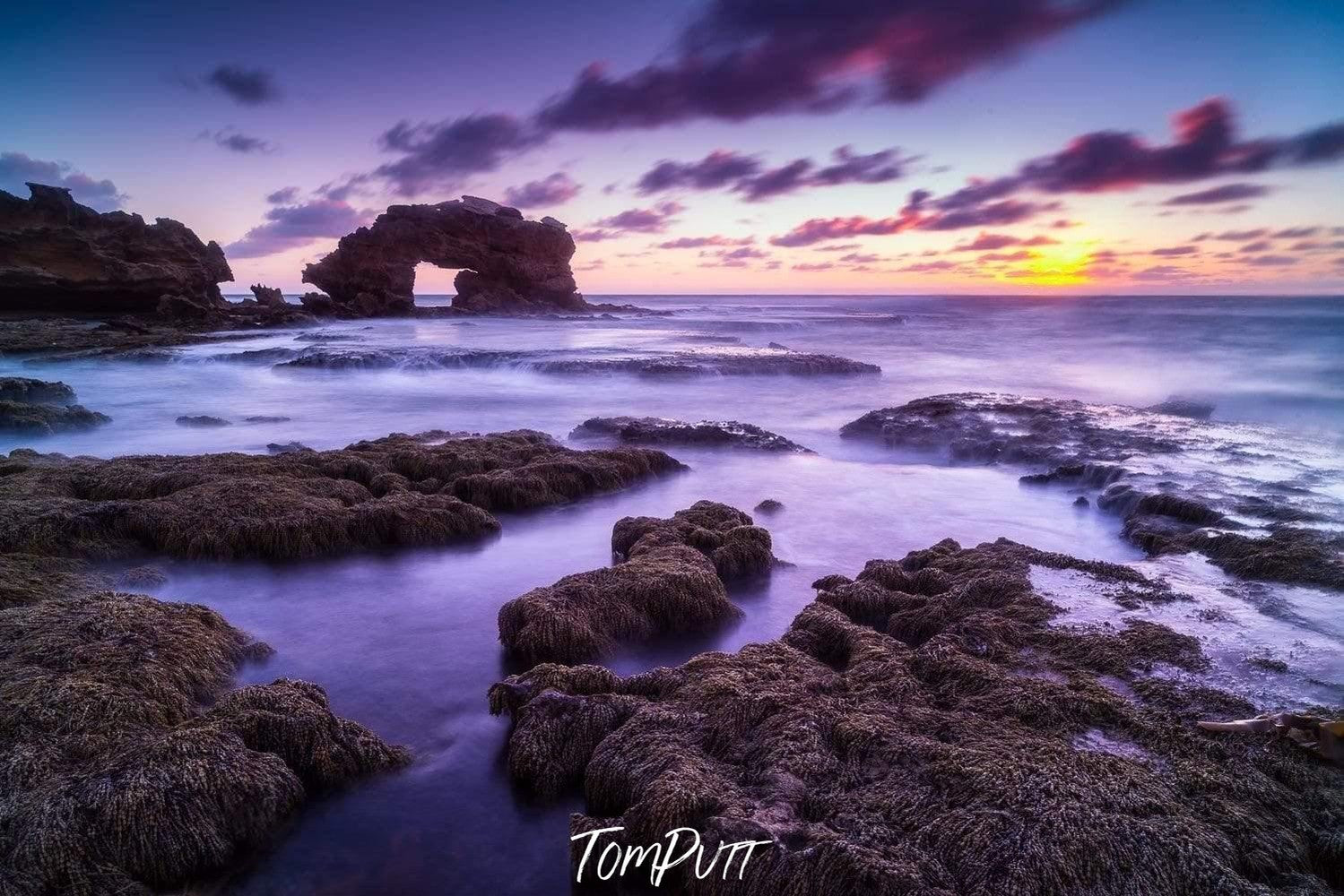 An early morning view of a sea with different shades of stones in the water and two large shapes of mountains rocks in the background, Bridgewater Bay - Mornington Peninsula VIC