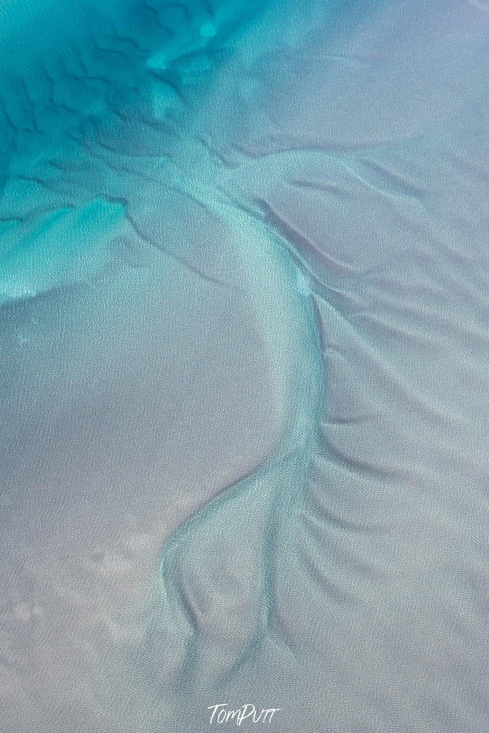 A portrait view of a sea-green colored ocean connecting with the land, spearing the green-colored lines on the land, Broome No.1