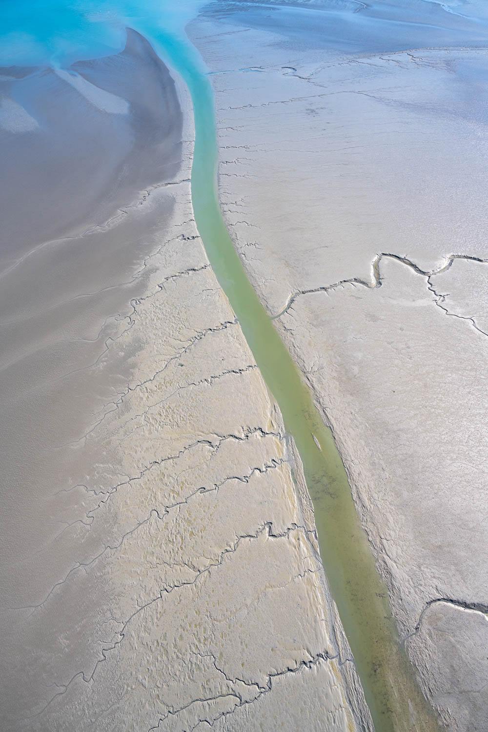 A beach-like land with a green-colored long line making a passage of water, and some cracks on the land, Broome #15 