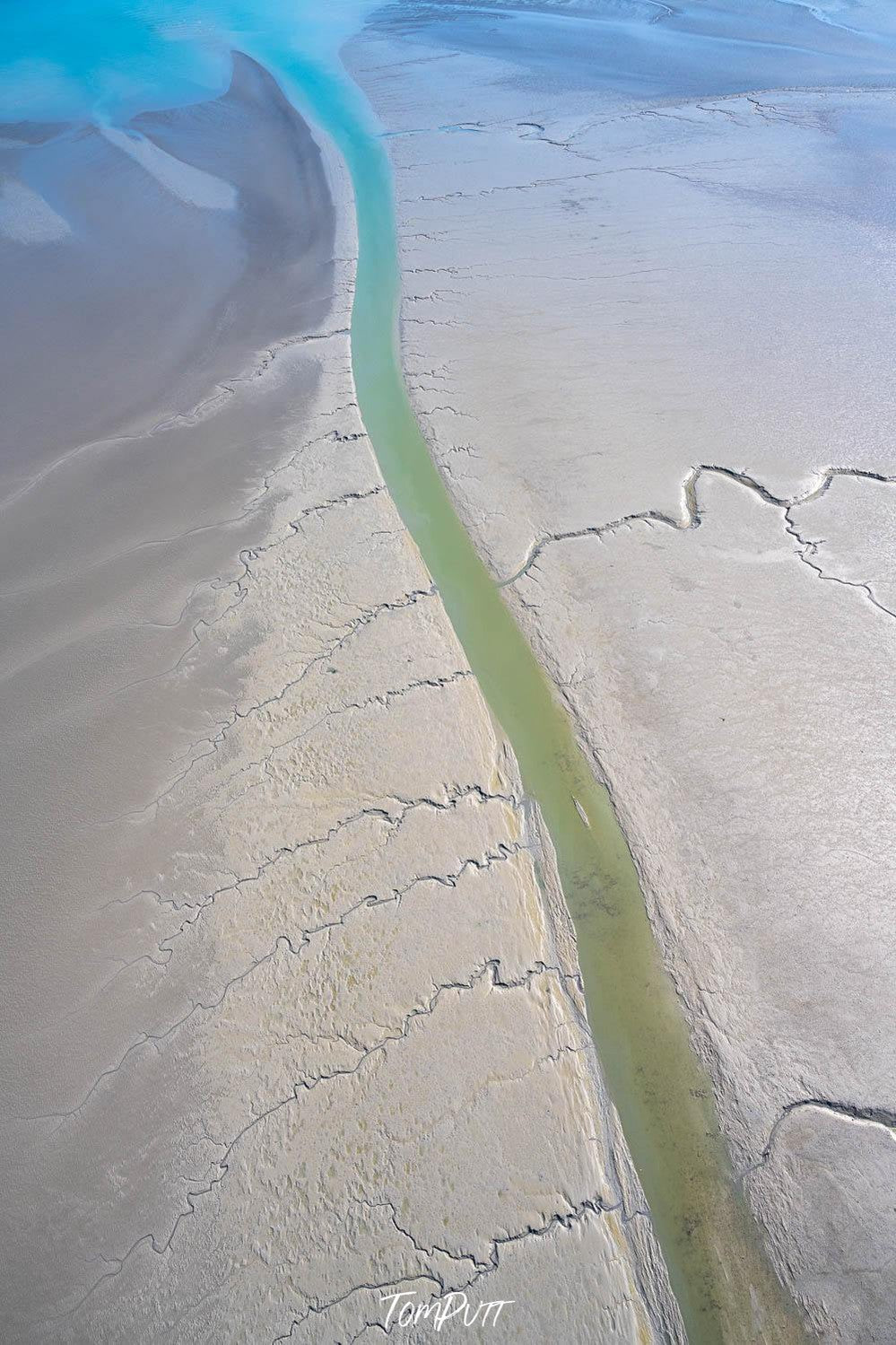 A beach-like land with a green-colored long line making a passage of water, and some cracks on the land, Broome No.15 