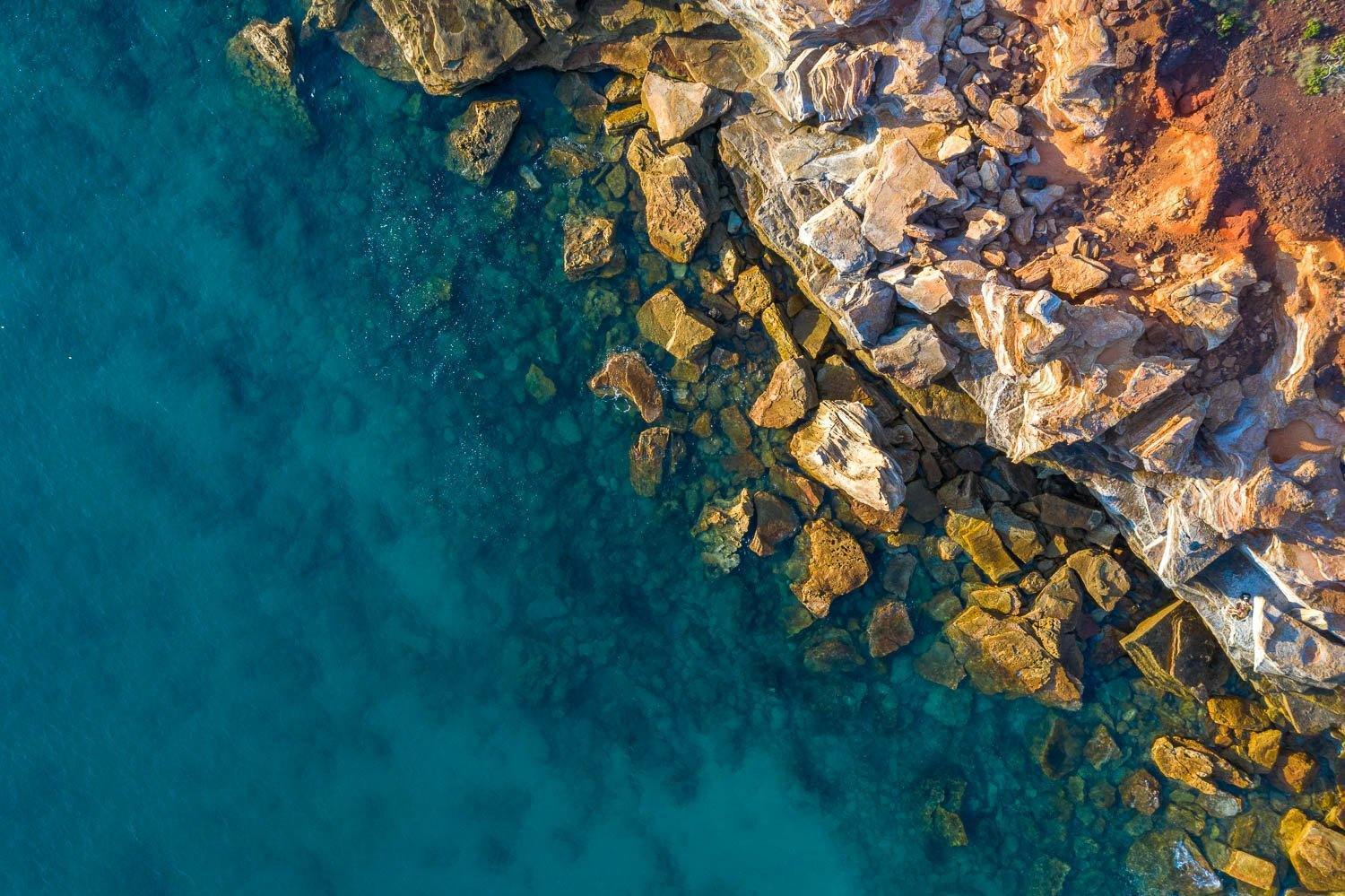 An aerial view of a lake corner with a lot of rocky stones, and an effect of the early sunlight falling on the scene, Broome #28