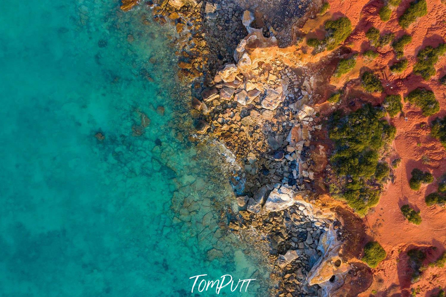 A long-shot aerial view of a lake corner with a lot of rocky stones, and an effect of the early sunlight falling on the scene, Broome No.29