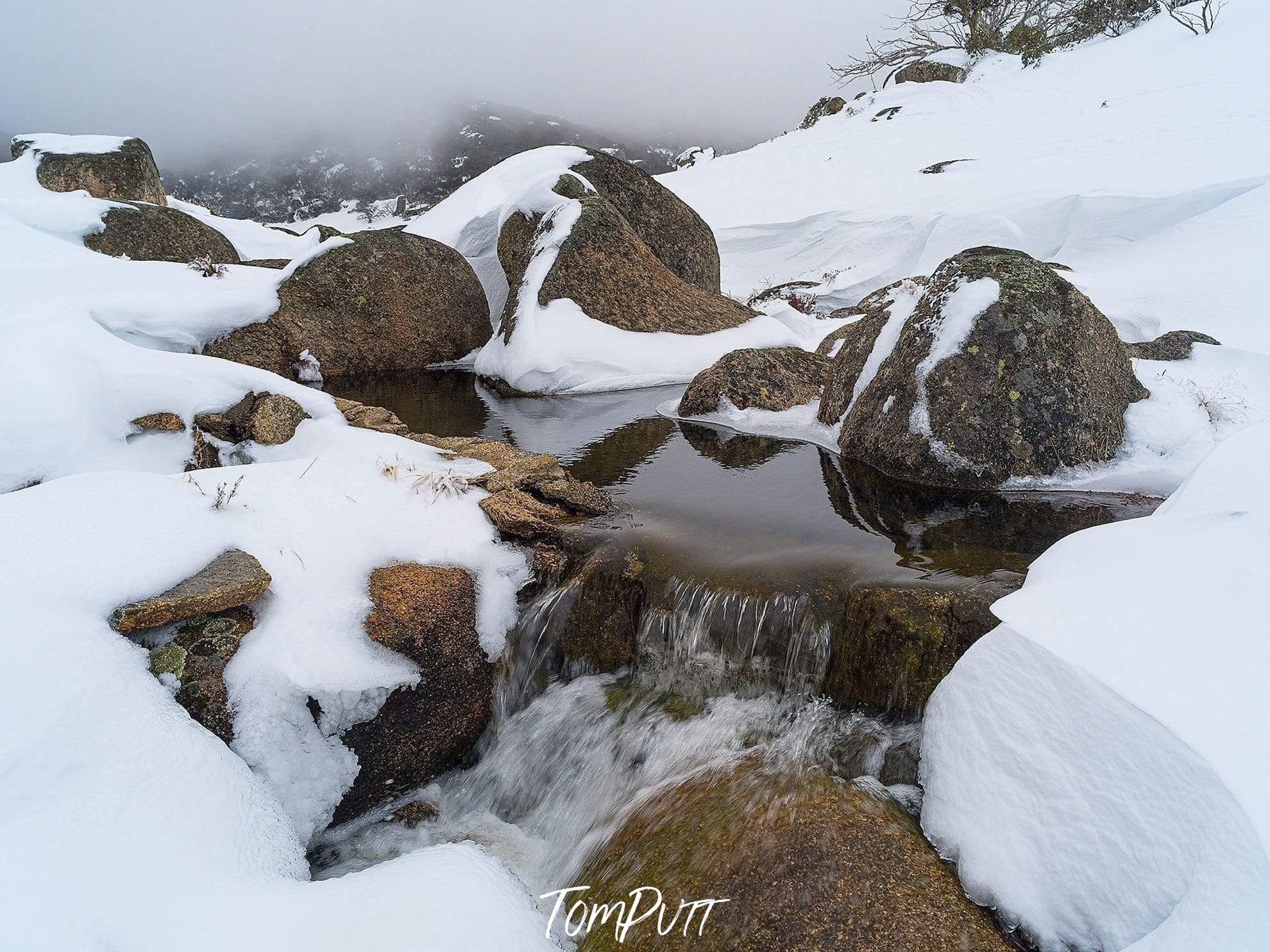 Buffalo Stream-Tom-A dense snow-covered area with some rounded stones partially exposed, and a little water flow between the stones, Buffalo Stream - Victoria High Country-Landscape-Prints