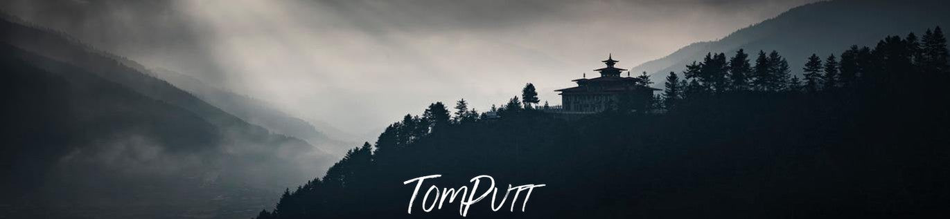 A dark view of a fort on the hillside of a mountain with some greenery, with some moonlight, and foggy effect, and a couple of giant blurred mountains in the far background, Bumthang Zhong - Bhutan