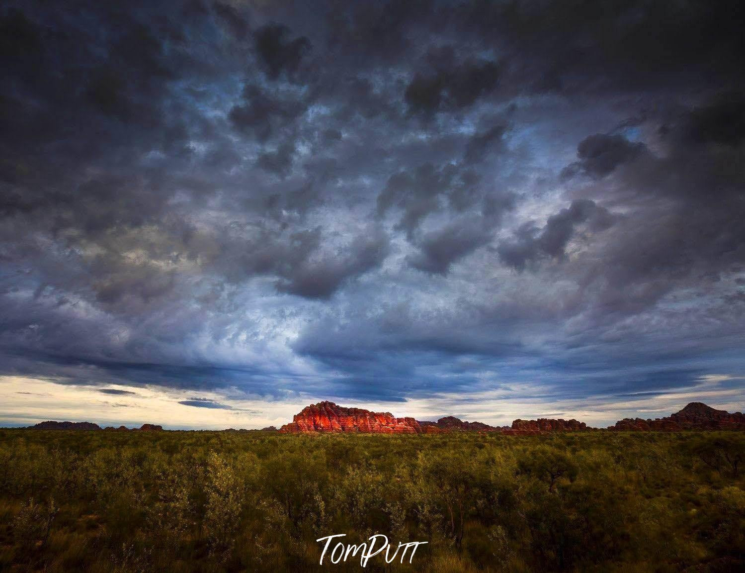 The great mountain wall with a giant black dense cloud over it, and a lush green field in the foreground, Bungle Bungle Storm - Purnululu Bungle Bungles