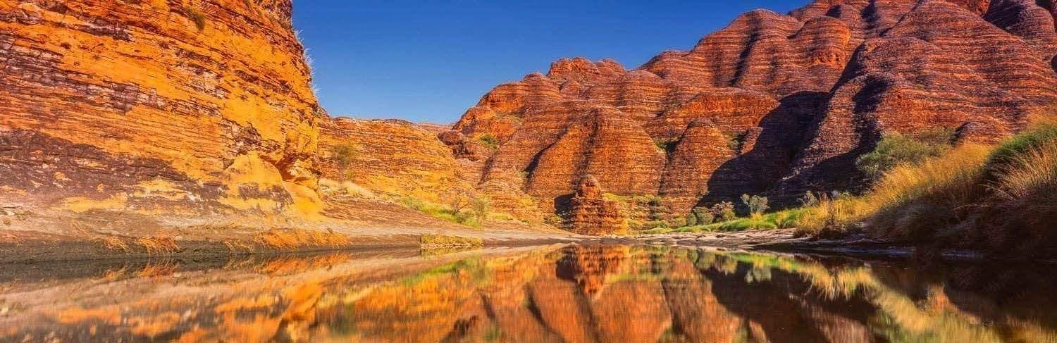 A beautiful sequence of similar mountains making a horizontal lines pattern with some grass on the edges, and a clear reflection of the scene in the watercourse, Bungles Reflection - Purnululu Bungle Bungles