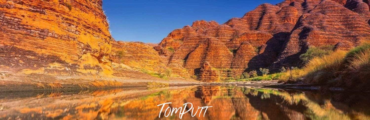 A beautiful sequence of similar mountains making a horizontal lines pattern with some grass on the edges, and a clear reflection of the scene in the watercourse, Bungles Reflection - Purnululu Bungle Bungles