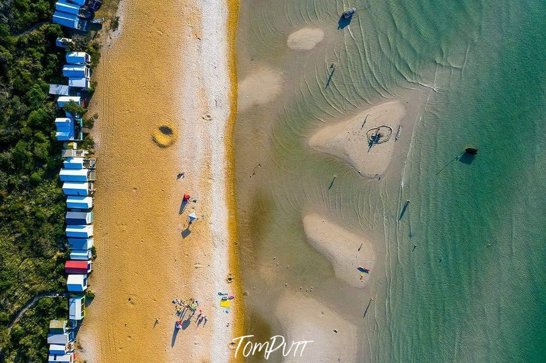 A long shot aerial view of a sea with little island-like land areas connecting with the land having a series of houses and a lot of greenery in the background, Bunker - Mount Martha, Mornington Peninsula