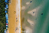 A long shot aerial view of a sea with little island-like land areas connecting with the land having a series of houses and a lot of greenery in the background, Bunker - Mount Martha, Mornington Peninsula
