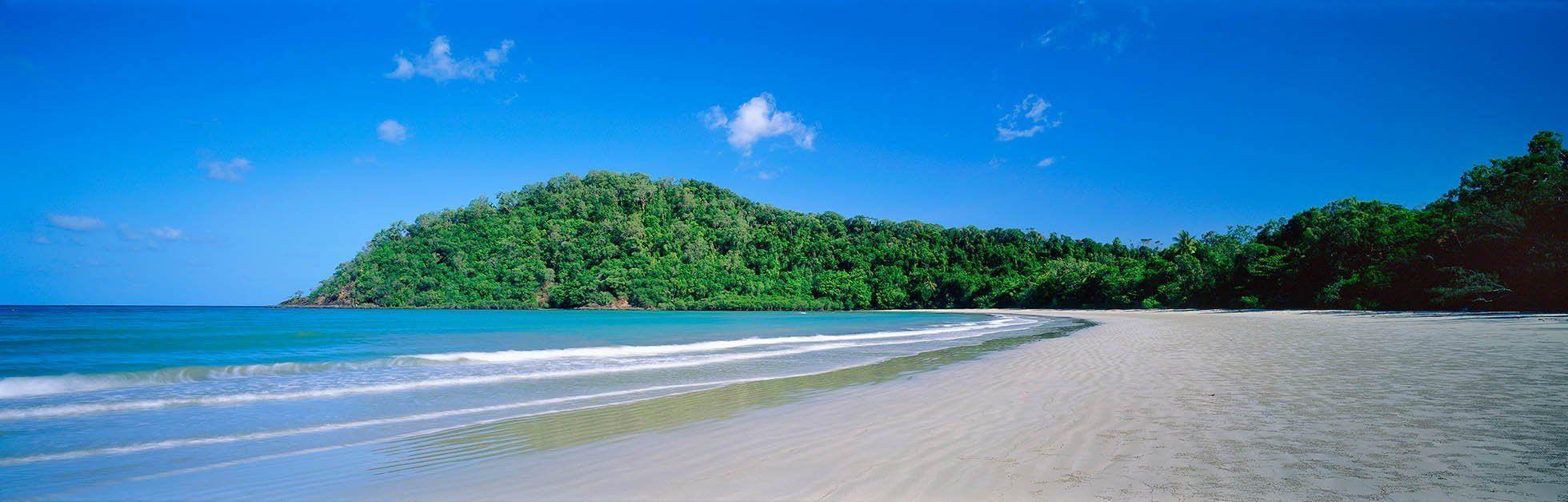A morning view of a beutiful long beach with clear blue color water in the foreground, and a wide series of fresh green trees, Cape Tribulation - The Daintree   