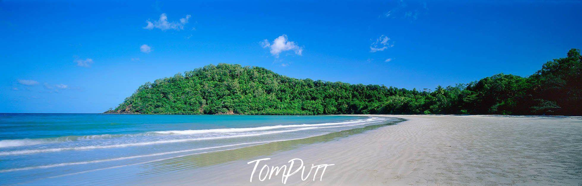 A morning view of a beutiful long beach with clear blue color water in the foreground, and a wide series of fresh green trees, Cape Tribulation - The Daintree   