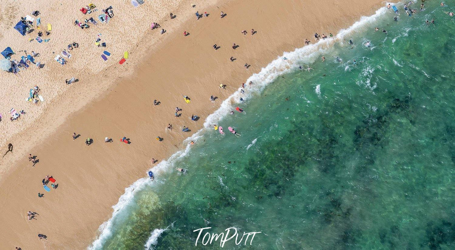 An aerial view of a deep sea-green colored beach connecting with the shore with so many huts and people on the beach enjoying their holiday, Catching Waves - Mornington Peninsula 