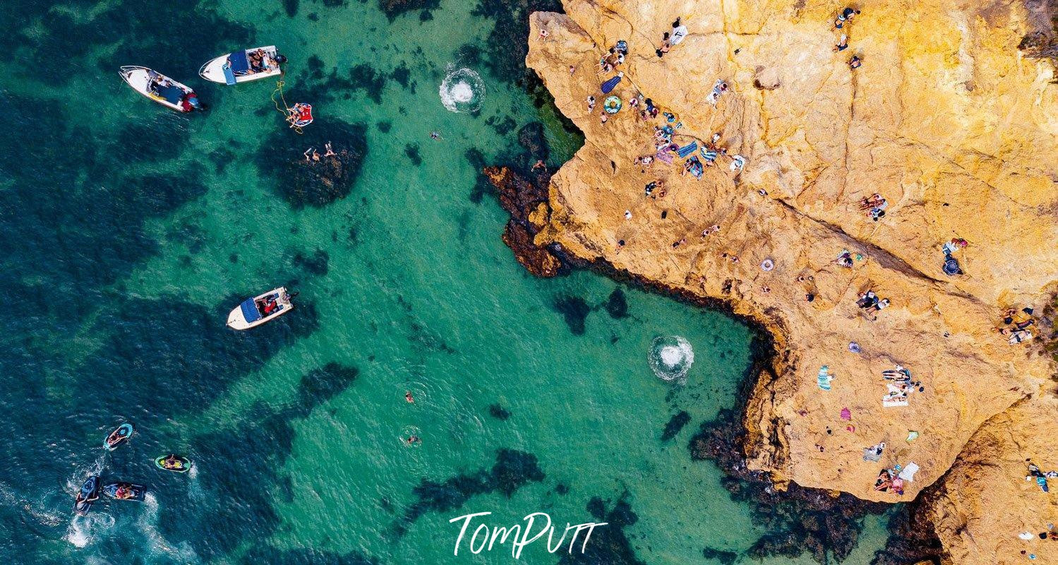 a deep sea-green color ocean having some boats in it with a giant rock serving as a beach for people, Circular Splashes - Mornington Peninsula