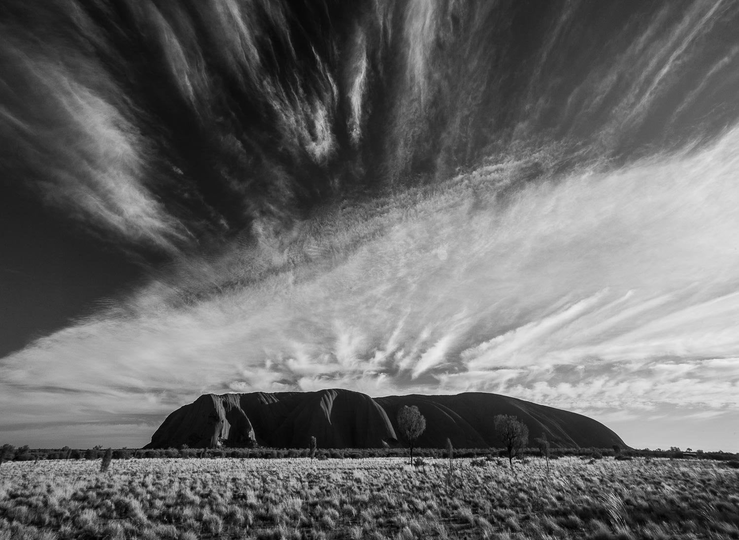Artwork of a giant wall of mountain making a retro effect of black and white sequence, fully covered with the black and white sky, Clouds streaming over Uluru, Northern Territory