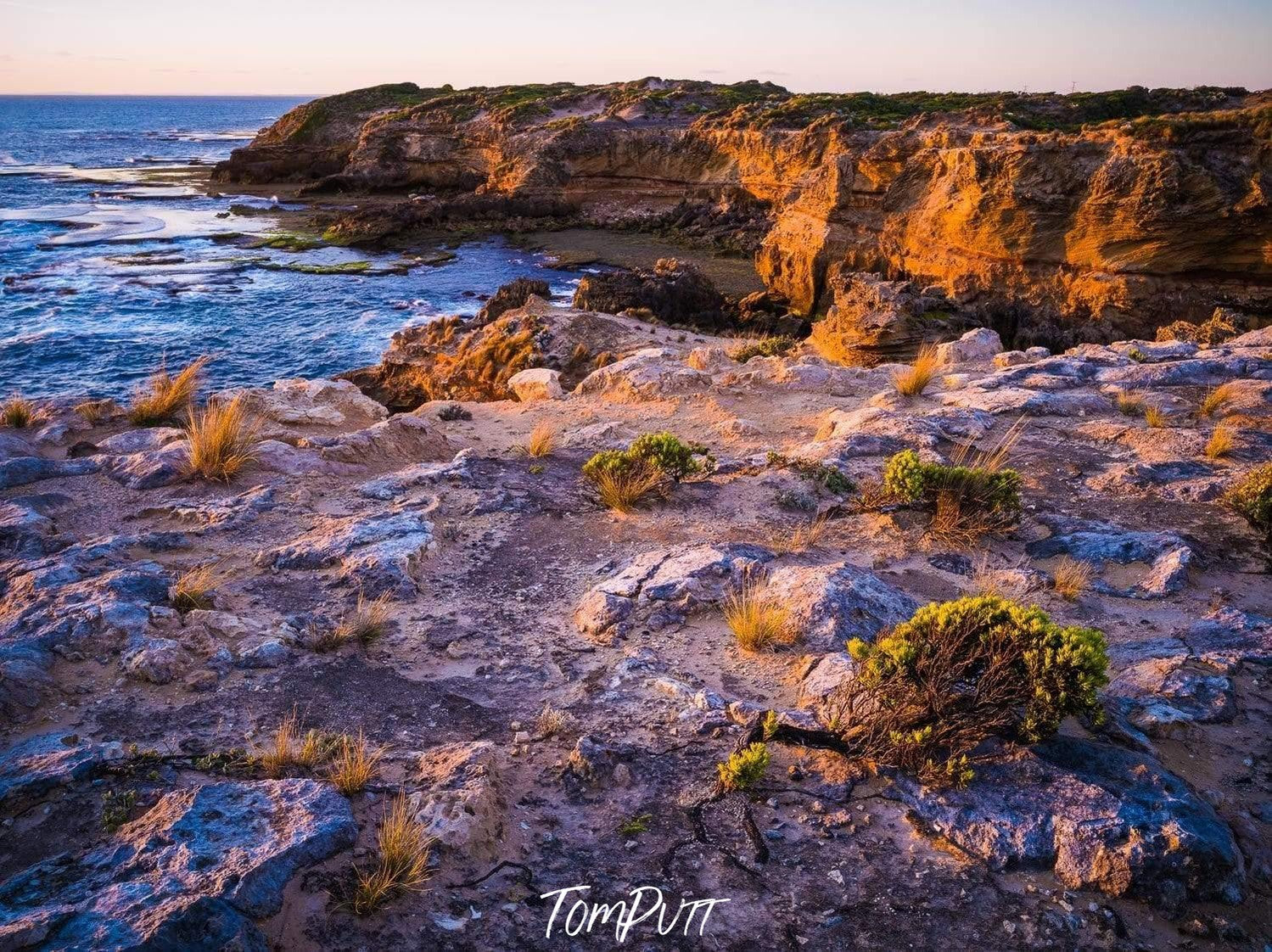 A daylight view of a long mountain wall with a sea corner some grass and bushes on the mountain and the land with clear sky blue water in the sea, Coastal Beauty, Rye - Mornington Peninsula VIC