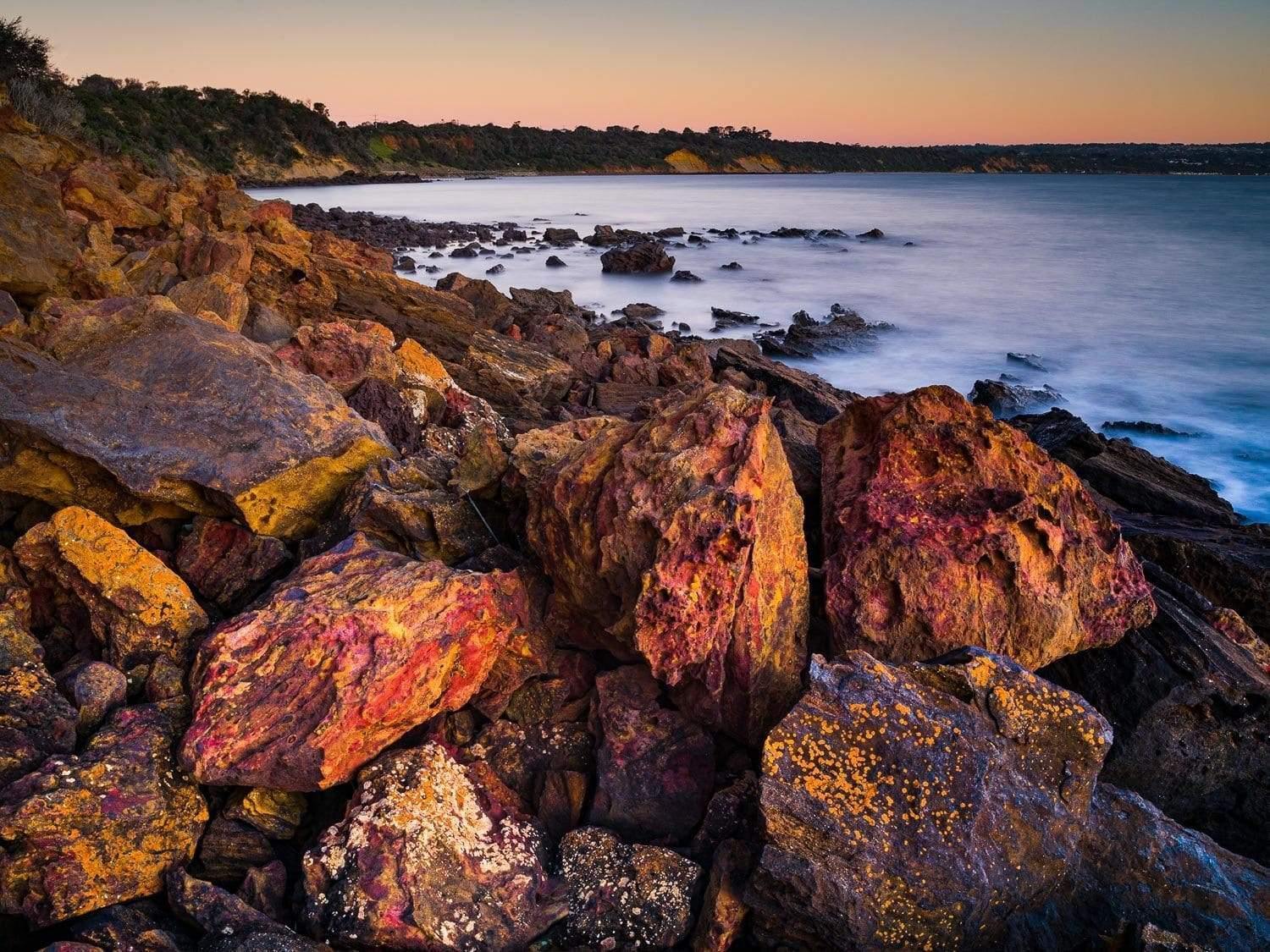 A closeup shot of rocky stones series with a natural texture and a seashore in the background, Coral Cove, Mt Martha - Mornington Peninsula Victoria