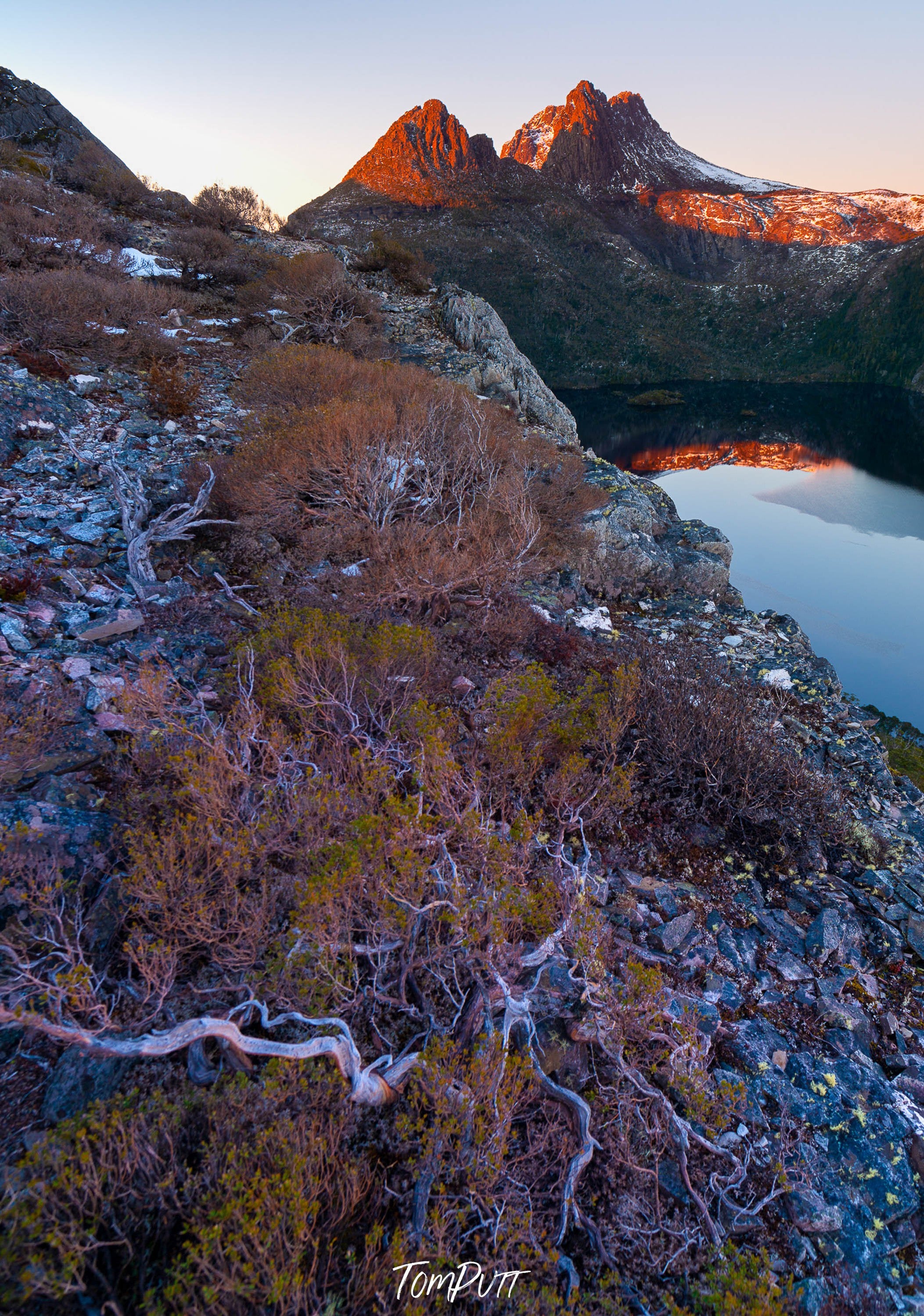 A rounded sequence of mountains wall with grass and bushes on them, and a lake below the boundary of the mountains, Cradle Mountain and Dove Lake early morning, Tasmania