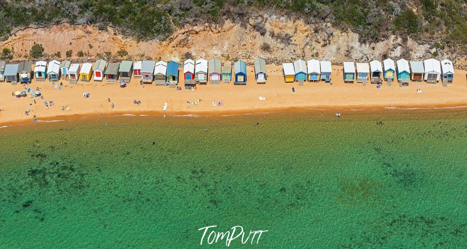 A long shot aerial view of a lake with green water and a series of huts at the seashore, Craigie Beach, Mt Martha - Mornington Peninsula Victoria   